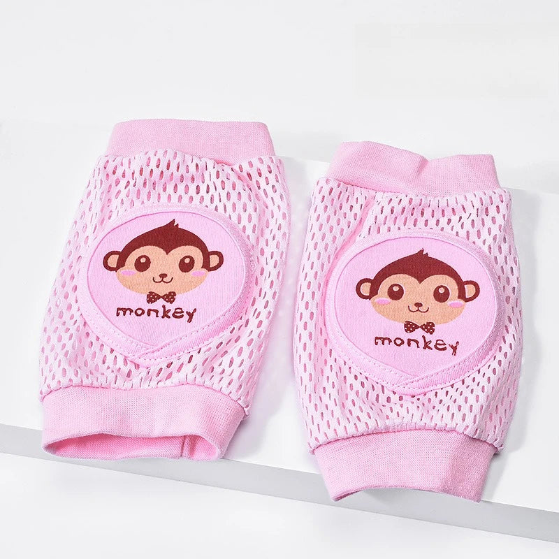 Pair of pink baby knee pads with monkey design on a white background